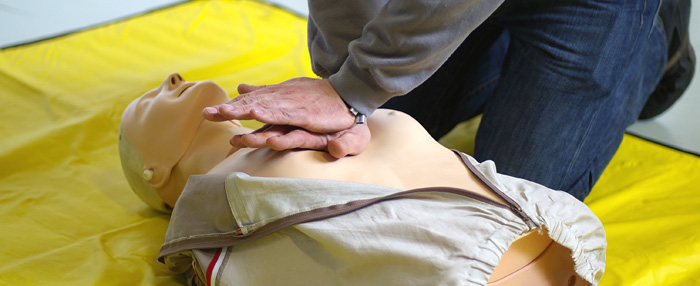 Ein Mann übt Herzmassage an einer Puppe. 