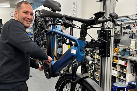 Monteur arbeitet an einem Fahrrad, welches für eine gute Körperhaltung angehoben ist.